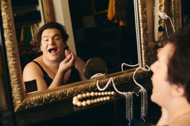 In a vibrant backstage dressing room, a drag queen applies makeup with flair, ready for the show. clipart