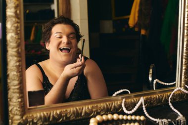Bir travesti, canlı bir soyunma odasında tatil öncesi makyajını zevkle yapar..