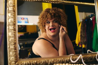 Bir travesti, tatil neşesiyle dolu bir kulis odasında makyaj yapar..