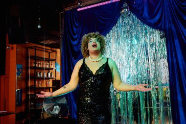 Çarpıcı bir travesti, kalabalığı cesur makyajıyla ve bir tatil gösterisinde abartılı bir kıyafetle büyülüyor..