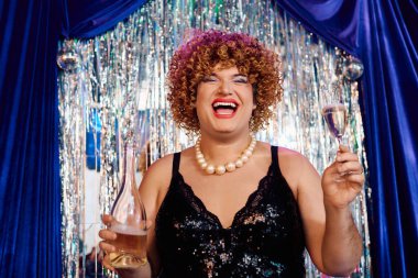 Canlı bir travesti, abartılı makyajı ve neşeli performansıyla seyirciyi büyülüyor..