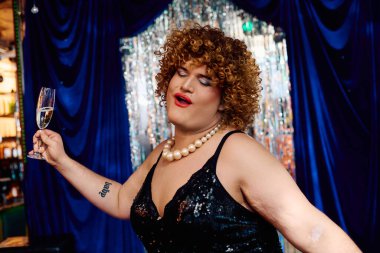 Göz kamaştırıcı makyajlı canlı bir travesti sahnede tutkuyla performans sergiliyor, çeşitliliği kutluyor..