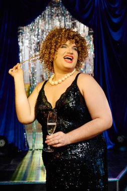 Bir travesti, şenlikli bir sahne performansı sırasında cesur makyaj ve savurgan bir stil sergiler..