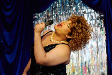 Şenlikli bir performans sırasında cesur makyajlı muhteşem travesti tutkuyla şarkı söylüyor..