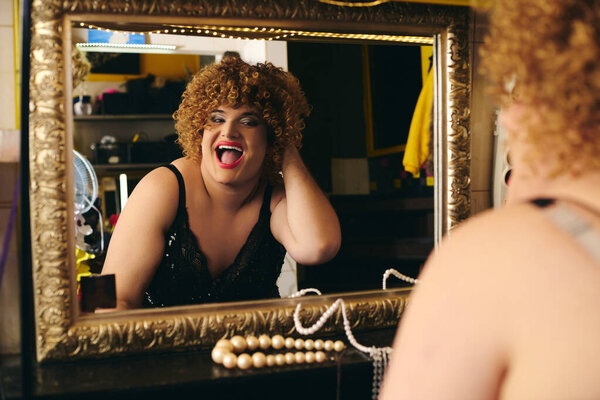 A drag queen masterfully applies makeup, readying for an exciting holiday show backstage.