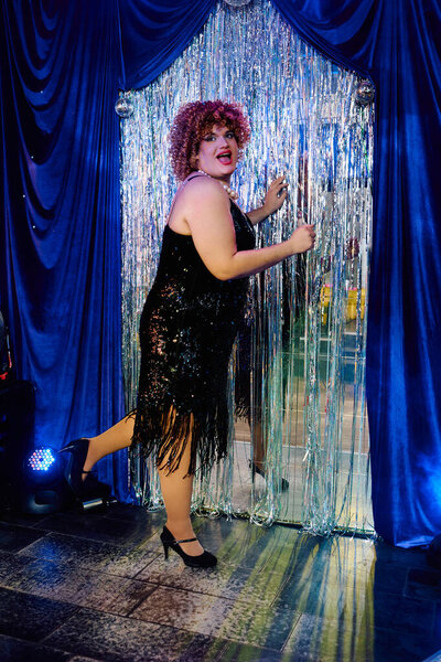 Перетащите королеву в гламурной одежде исполняет страстно на сцене, демонстрируя яркий макияж и чутье.