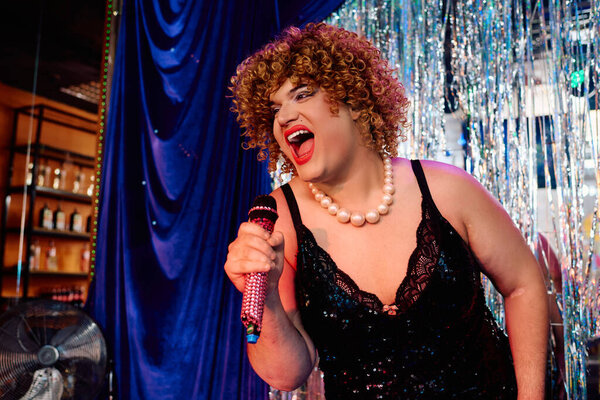 Королева трансвеститов ослепительна на сцене в сказочном макияже и наряде на празднике.