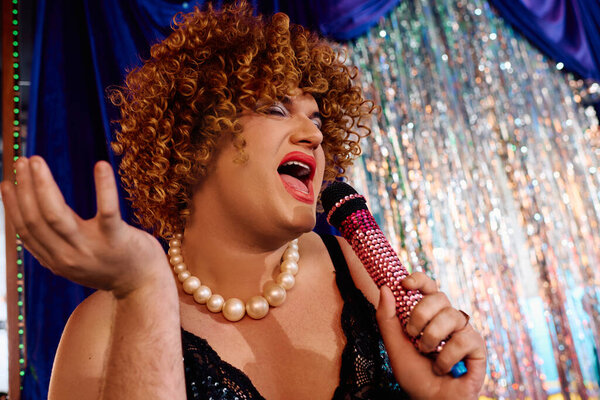 Королева трансвеститов с ярким макияжем привлекает толпу во время экстравагантного праздничного представления.