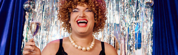 Королева трансвеститов со смелым макияжем радостно развлекает зрителей на сцене во время праздничного мероприятия.