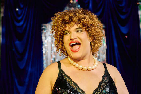 Eccentric drag performer showcases vibrant makeup and stunning costume at festive event.