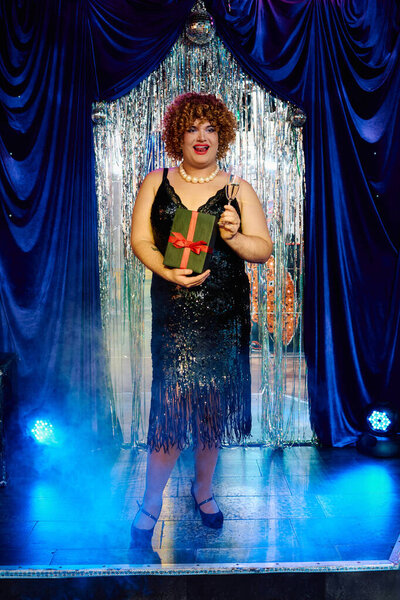 Яркая трансвестит очаровывает зрителей экстравагантным праздничным представлением на сцене.