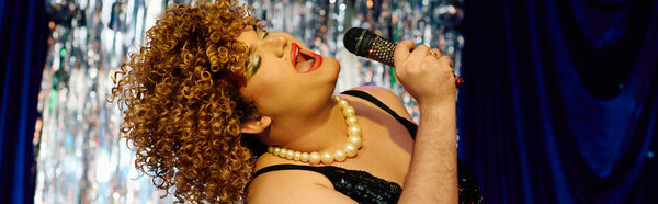 Королева трансвеститов светится на сцене, демонстрируя экстравагантный макияж и яркий наряд во время выступления.