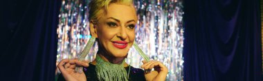 Karizmatik bir travesti, bir tatil gösterisinde kalabalığı cesur makyajı ve enerjik enerjisiyle büyülüyor..