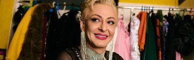 A drag queen applies vibrant makeup in a bustling backstage dressing room, ready for a show. clipart