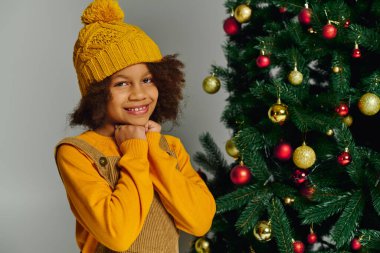 Güzel süslenmiş bir Noel ağacının yanında sıcacık gülümseyen neşeli kız.