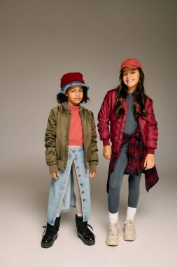 İki küçük kız şık kıyafetler içinde birlikte poz veriyor, 2025 'te Noel' i mutlu bir şekilde kutlamaya hazırlar..