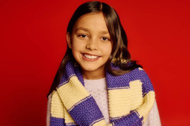 Smiling girl wearing a cozy scarf, radiating joy and festive cheer in a vibrant atmosphere. clipart