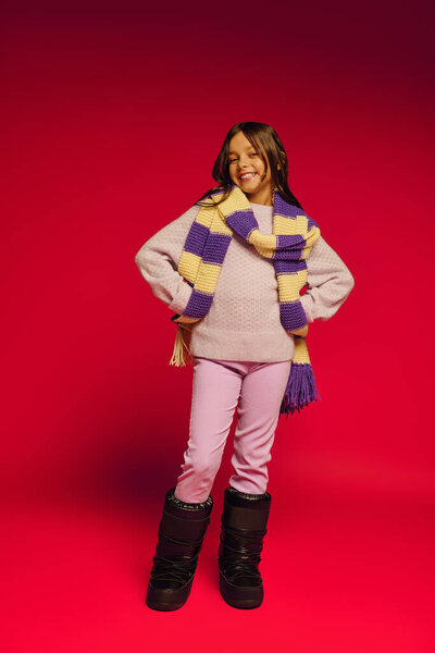 Веселая девушка позирует в уютном зимнем наряде, обнимая праздничный дух Рождества 2025 года.