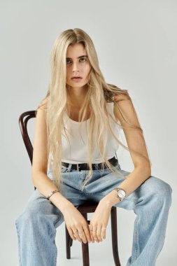 Genç bir kadın, sıradan bir kıyafetle zarif bir şekilde poz verir. Stüdyoya güzellik ve güven saçar..