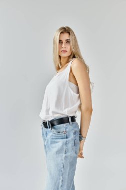 Uzun sarı saçlı, kendine güvenen genç bir kadın şık bir bluzla modern moda modelleri..