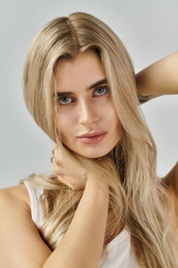 Şık bir stüdyoda, göz kamaştırıcı sarı saçlı genç bir kadın moda gösterisi yapıyor..