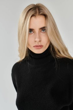 Uzun sarı saçlı güzel bir kadın. Minimalist bir ortamda siyah bir elbise..