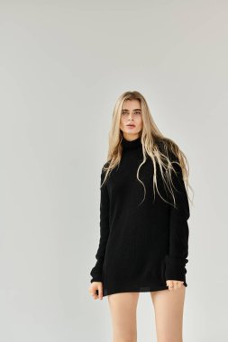 Uzun sarı saçlı genç kadın modern bir stüdyo ortamında moda zarafeti sergiliyor..