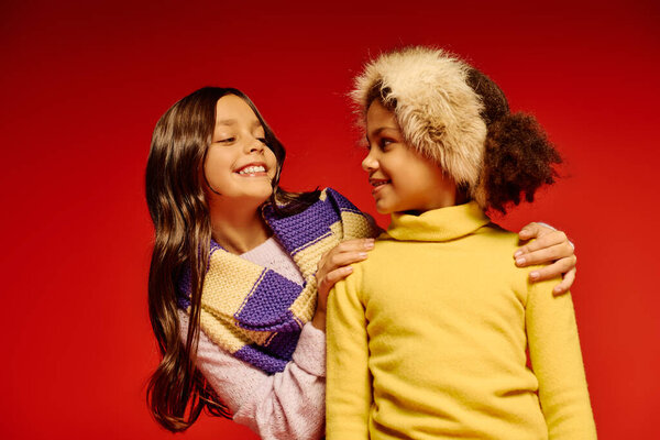 Две веселые девушки в контрастных нарядах делятся радостным смехом во время рождественских праздников.