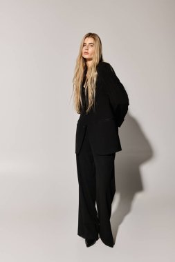 Sarışın kadın şık siyah bir elbise içinde modern güzellik eğilimleri sergiliyor..