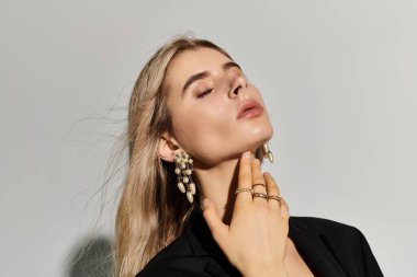 Güzel, genç bir kadın, kendine güvenen bir şekilde siyah elbisesiyle poz verir, zarafetini ve tarzını ön plana çıkarır..