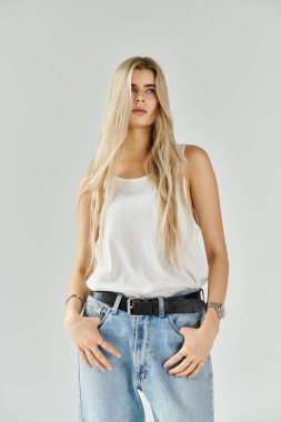 Parlak stüdyo, şık bir bluz ve kot pantolon giyen, kendine güveni olan güzel bir genç kadına ev sahipliği yapar..