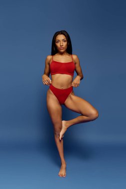 Kendine güvenen genç bir Afrikalı Amerikalı kadın stüdyo ortamında şık iç çamaşırı modelliği yapıyor..