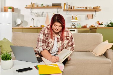 Focused plus size woman writes notes and ideas while seated comfortably in her cozy living space. clipart