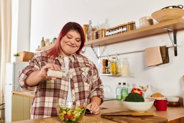 Genç kadın, sıcak mutfağında taze malzemelerle dolu renkli bir salata sezonu geçiriyor..