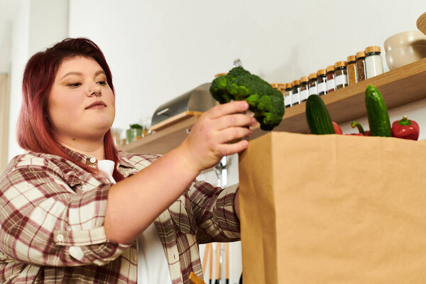 Young woman carefully places fresh broccoli into a brown paper bag in her cozy kitchen
