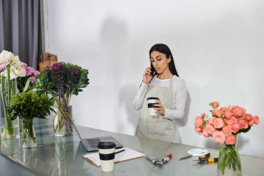 A florist organizes vibrant flowers while communicating with a client over the phone. clipart