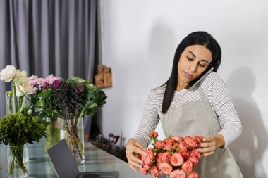 Esmer çiçekçi büyüleyici bir buket hazırlıyor. Çiçekçi dükkanındaki aramaları dengeliyor..