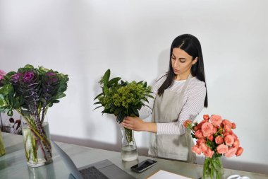 Esmer çiçekçi ustalıkla dükkanında taze çiçek hazırlıyor, yeteneğini sergiliyor..