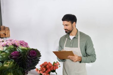 Bearded man meticulously arranges flowers while managing his small business with care. clipart