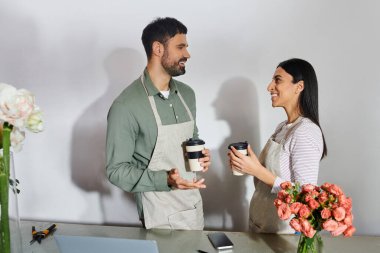 A married couple works together in their flower shop, exchanging ideas and enjoying their passion. clipart