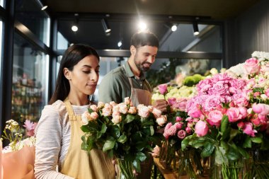 This couple joyfully arranges colorful flowers together in their cozy flower shop. clipart