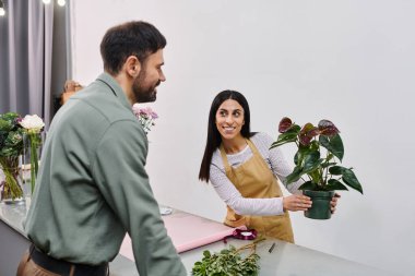 A skilled florist assists a man in selecting beautiful plants during a friendly visit. clipart