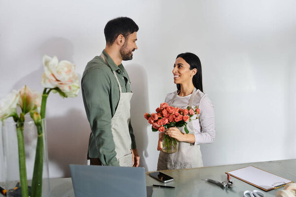 Married florists collaborate joyfully to craft stunning floral designs in their shop.