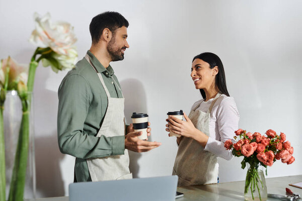 Two florists share a moment while talking near floral arrangements in their cozy shop.