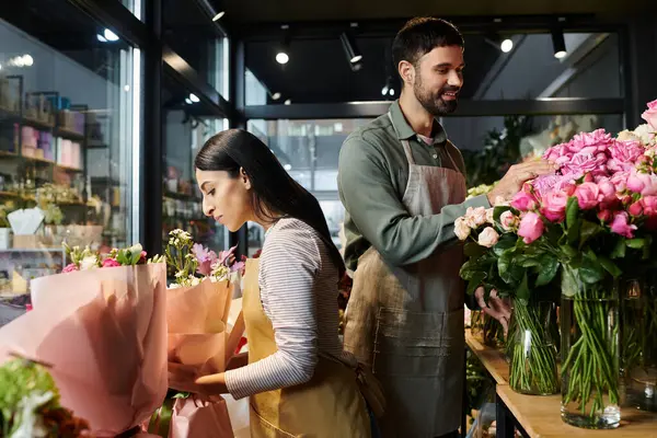 Bir çift çiçekçi dükkanında ahenkli bir şekilde çalışıyor, güzel buketler ve düzenlemeler yapıyorlar..