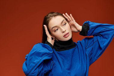 Şık bir kadın, kendine güveni tam kırmızı bir zemine karşı poz verir. Benzersiz modayla hava atar..