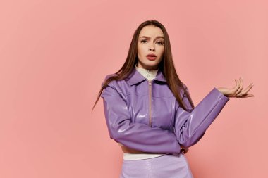 Canlı stil sahibi bir kadın pembe bir arka plana karşı duruyor, eşsiz moda anlayışını sergiliyor..