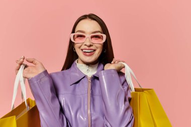 A stylish woman with a cheerful smile enjoys a shopping spree, holding bright yellow bags. clipart