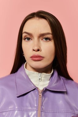 Mor elbiseli şık bir kadın, pembe bir arka plana güvenerek poz verir..