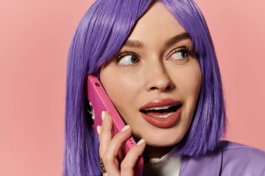 Mor saçlı canlı bir kadın pembe telefonuyla canlı bir konuşma yapıyor..